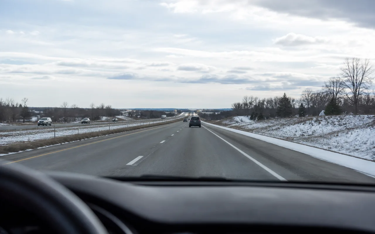 Highway driving scene in winter daylight approaching a border-region crossing, no readable signage or plates